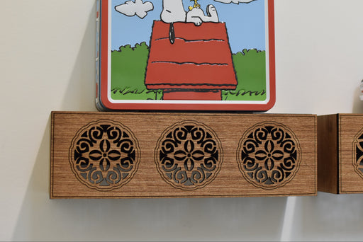 Wooden shelf with decorative cutouts and a small figurine on a plain background