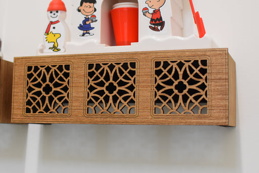 Wooden shelf with decorative cut-out patterns and small figurines on a white background