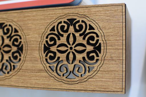 Wooden box with intricate black laser-cut patterns on a white background